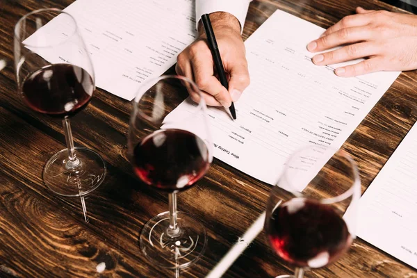 stock-photo-cropped-view-sommelier-writing-documents-table-wine-glasses